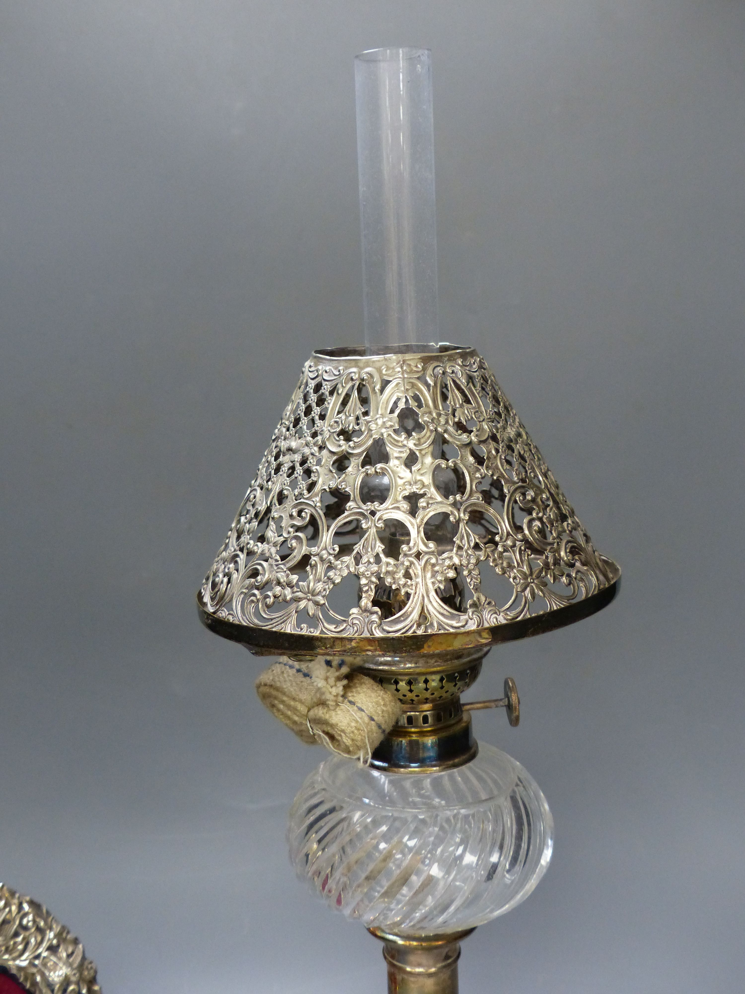 A Victorian plated oil lamp with white metal shade together with a Victorian silver mounted frame